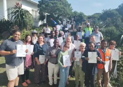 Group of diverse people holding certificates outdoors, celebrating sustainable green landscape solutions.