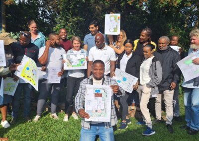 Colorful landscape design plans showcased by a diverse group of architects and community members outdoors.