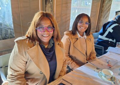 Bright smiling women in beige jackets at eco-friendly meeting, promoting green landscaping solutions.