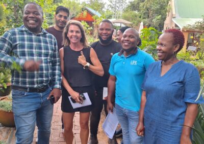 Lush garden with diverse plants and smiling people engaging in sustainable landscaping efforts.